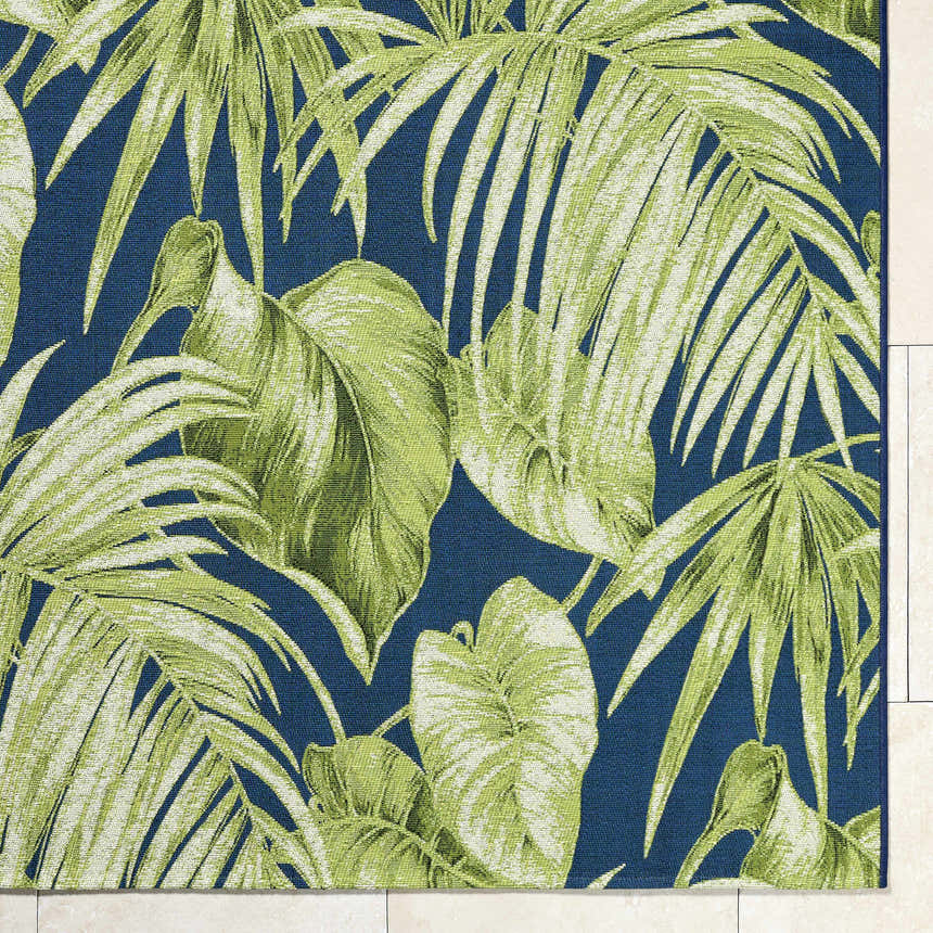 Close-up of Amirah Teal Area Rug featuring a vibrant green tropical leaf pattern on a textured navy blue background. Corner