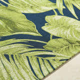 Close-up of the Amirah Teal Area Rug featuring a vibrant green leaf pattern on a deep teal background. Coastal style. Texture