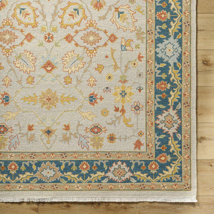 Close-up of the hand-knotted Yenimahalle Premium Rug. Beige rug with burnt orange, ice blue, and mustard floral pattern. Corner