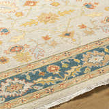 Close-up of the Yenimahalle Premium Rug. Hand-knotted wool rug in beige, teal, burnt orange, and mustard floral pattern. Texture