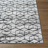 Close-up of the contemporary Yaqub Area Rug. Black geometric pattern on a gray, off-white, and white textured background. Front