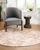 Living room scene with gray chair and round Yakov Area Rug in cream and tan. Roomscene-Round
