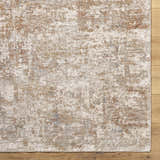 Close-up of the Yakov Area Rug. Cream, tan, and blue abstract pattern on a textured polyester rug. Corner
