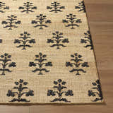 Close-up of the Albina Florentine Jute&Wool Rug. Black floral pattern on a beige, hand-woven jute rug with wood floor. Front
