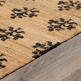 Close-up of the Albina Florentine Jute & Wool Rug. Natural jute rug with a black floral pattern and woven texture. Pile