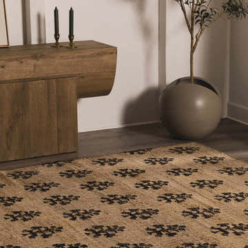 Contemporary room scene with a jute Albina Florentine rug, wood cabinet, olive tree, and neutral tones. Roomscene-Rectangle