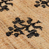 Close-up of Albina Florentine rug showing jute texture and black floral pattern. Contemporary hand woven rug. Texture