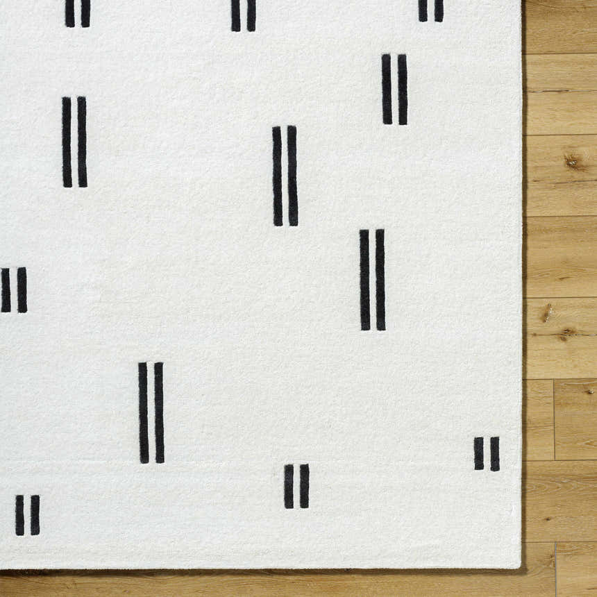 Close-up of the Yitta Ivory Area Rug showing its ivory wool texture and jet black vertical line pattern. Corner
