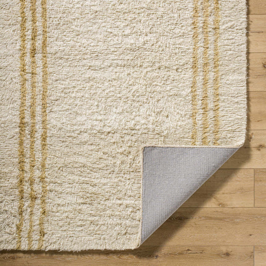 Close-up of the Yahto Area Rug showing its camel stripes, soft wool texture, and durable gray backing. Fold