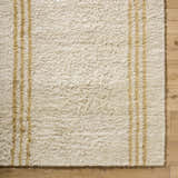 Close-up of the hand-tufted Yahto Area Rug. Camel and tan stripes on a pearl wool rug with a soft, shaggy texture. Corner