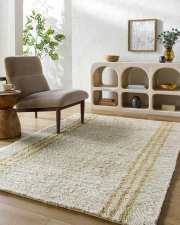 Living room scene with a camel chair and the Yahto Area Rug in cream with tan stripes. Roomscene-Rectangle