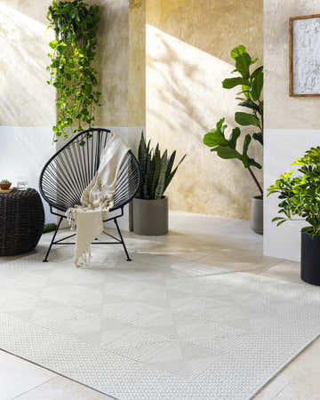Sunlit patio scene with Anabia White area rug, black chair, and potted plants creating a relaxing, modern farmhouse vibe. Roomscene-Rectangle