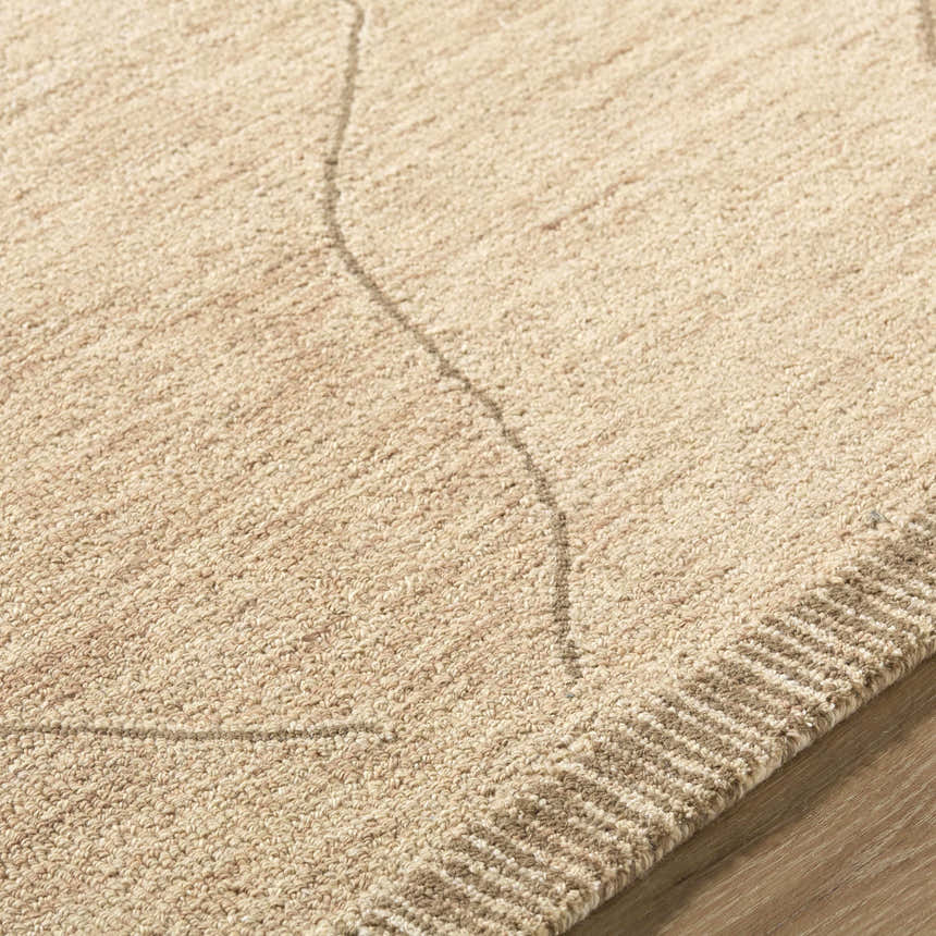 Close-up of the hand-tufted Addien Area Rug. Neutral beige wool rug with subtle geometric line pattern and textured border. Texture