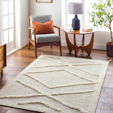 Living room scene with a beige Yutu Area Rug, gray chair with orange pillow, and mid-century modern side table. Roomscene-Rectangle