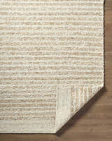 Close-up of the hand woven Yaron Area Rug. Jute and wool rug with pearl and tan horizontal stripes. Fold