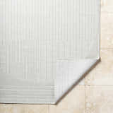 Close-up of the textured, light silver Yuley White Area Rug showing the edge detail and folded corner. Fold