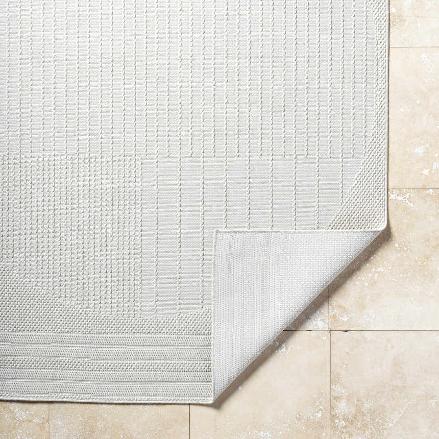 Close-up of the textured, light silver Yuley White Area Rug showing the edge detail and folded corner. Fold