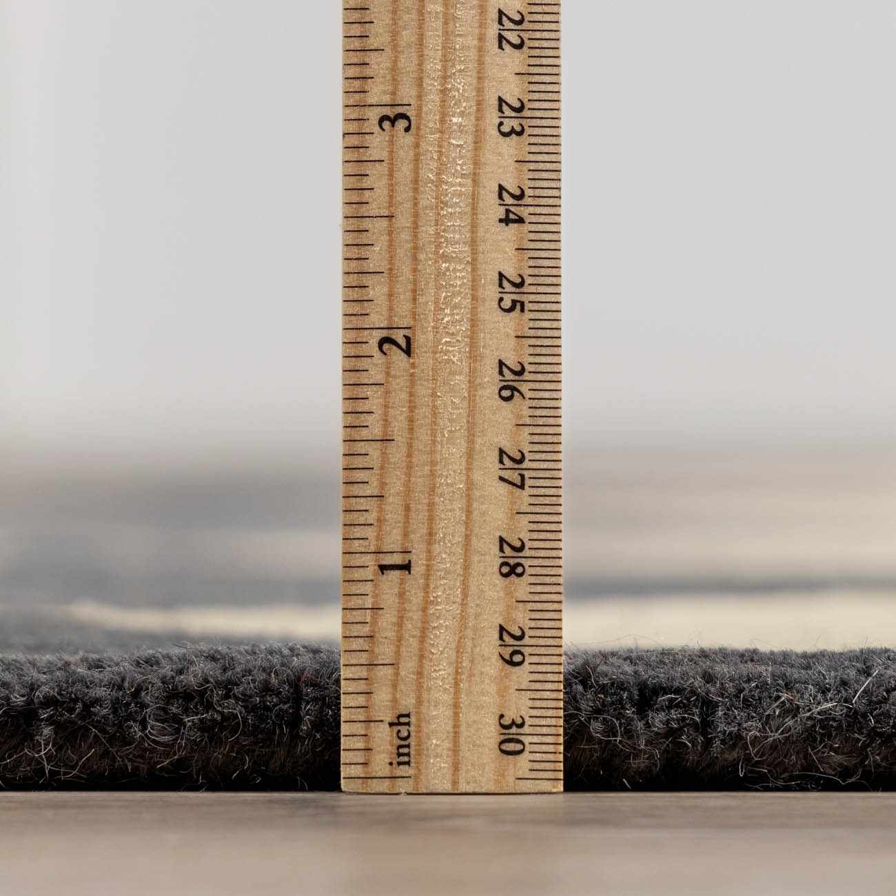 Close-up of the Aradia Charcoal Area Rug showing its pile height with a ruler. Pile