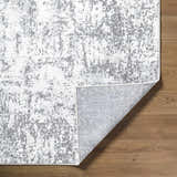 Close-up of the Alviva Area Rug showing its charcoal, gray, and white contemporary pattern and texture on wood floor. Fold