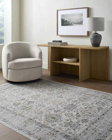 Living room scene with a light gray Aleron Area Rug, chair, wood console table, lamp, and artwork. Roomscene-Rectangle