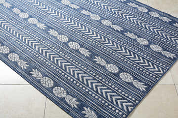 Close-up of Zaida Blue Area Rug with a blue and cream pineapple and geometric pattern. Corner