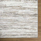 Close-up of the Aminia Area Rug. Contemporary design in charcoal, gray, light brown, and white on a wood floor. Corner