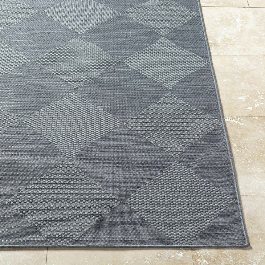 Close-up of the gray Aulani Area Rug with a diamond pattern on beige tile flooring. Front
