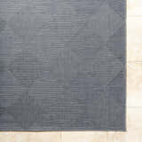 Close-up of gray Aulani Area Rug with diamond pattern on beige tile floor. Contemporary style. Corner