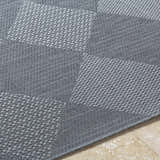 Close-up of the gray Aulani Area Rug showing its woven texture and geometric square pattern. Texture