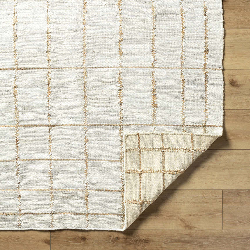 Close-up of the hand woven Zared Checkered Jute Area Rug with ash and light silver tones on a wood floor. Fold