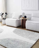 Living room scene with the Zytka Area Rug, featuring a desert sand and silver gray circular pattern. White armchairs and decor. Roomscene-Rectangle