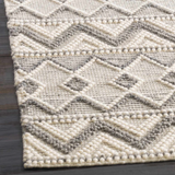 Close-up of the hand woven Whittington Gray&Cream Wool Rug, featuring a geometric diamond pattern and textured wool. Corner