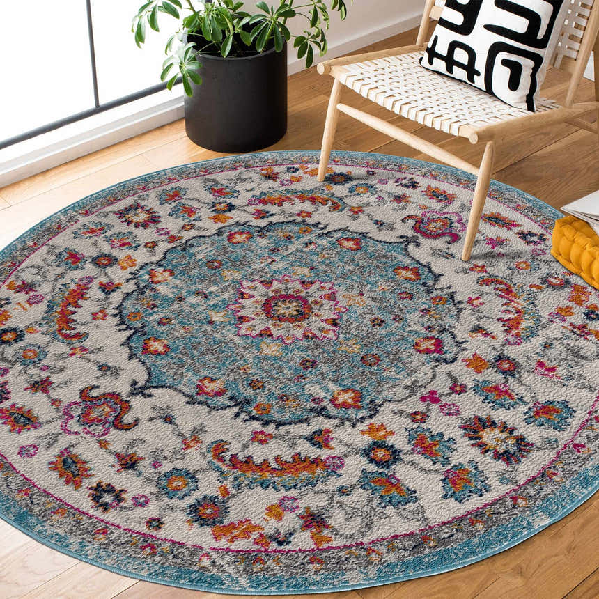 Bohemian style round Tigril Blue 2303 Area Rug in a living room with wood floors, chair, and plant. Beige, ivory, and turquoise rug. Roomscene-Round