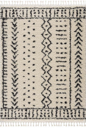 Close-up of the Hauppauge Berber Shag Carpet. Light beige rug with black geometric patterns and tassels. Shag texture. Design-Rectangle-5373