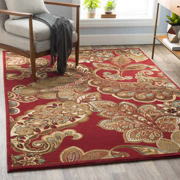 Living room scene with Beedeville Red Floral Rug, gray armchair, wood floors, and natural light from the window. Roomscene-Rectangle