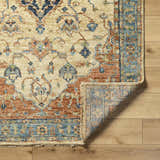 Close-up of the hand-knotted Bowlus Area Rug. Features a traditional floral pattern in aqua, brick red, brown, and ivory. Fold