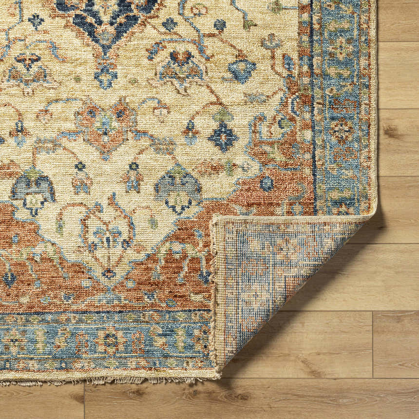 Close-up of the hand-knotted Bowlus Area Rug. Features a traditional floral pattern in aqua, brick red, brown, and ivory. Fold