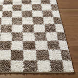 Close-up of the Neftekamsk Area Rug, showing a brown and white checkerboard pattern and soft, shaggy texture. Front