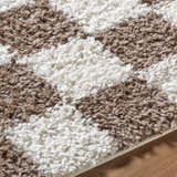 Close-up of the plush Neftekamsk Area Rug. Features a shaggy pile with an abstract pattern in white and brown. Texture