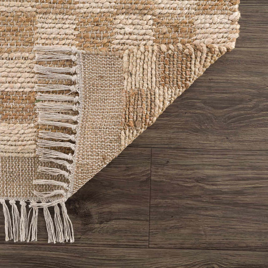 Close-up of the Ionut Checkered Jute Area Rug showing beige and tan checkered pattern, jute texture, and decorative fringe. Fold