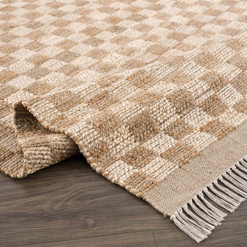 Close-up of the hand-woven Ionut Checkered Jute Area Rug. Beige and tan checkerboard pattern with jute texture and fringe. Fold