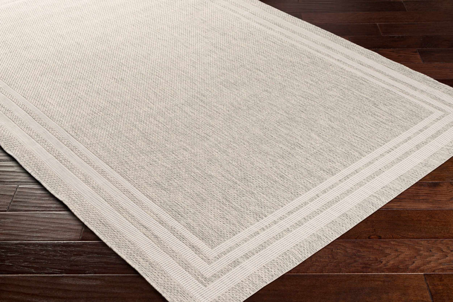 Close-up of the beige and gray Burradoo Bordered Area Rug showing the textured weave and striped border detail. Corner