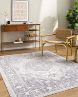 Living room scene with Odeon Elle Decor x LIVABLISS rug in charcoal, cream, and gray. Console table, woven chair, and plant. Roomscene-Rectangle