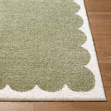 Close-up of Rivoli Elle Decor x LIVABLISS EDRV-2303 rug. Olive green rug with cream scalloped border on wood floor. Front