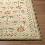 Close up of a hand-tufted Acacia Area Rug. Farmhouse style wool rug with floral pattern in beige, pink, and green on wood floor. Front