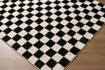 Close-up of the Naye Cream Color Block rug with black and cream checkered pattern on wood floor. Corner
