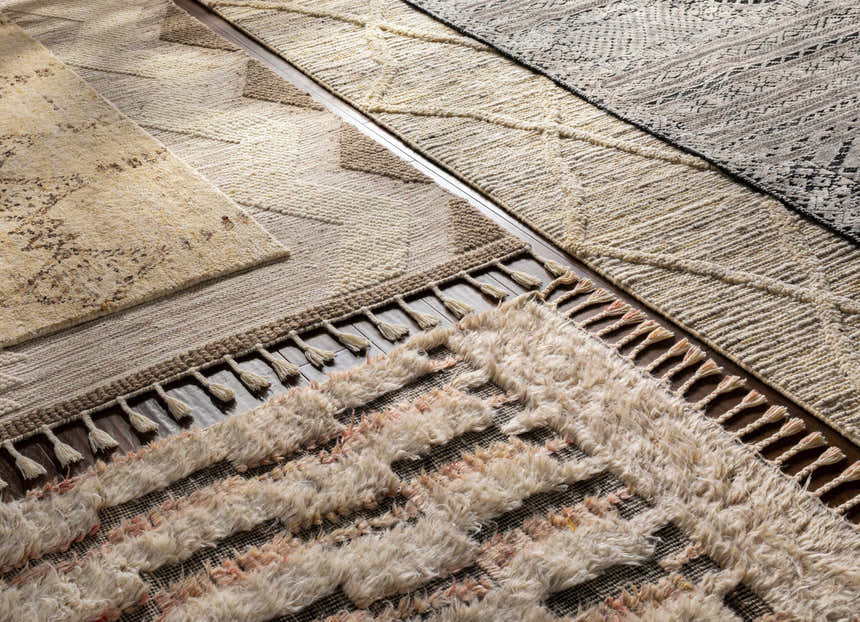 Close-up of Donsol Area Carpet, a hand-woven wool rug with cream, brown, charcoal, and black bohemian patterns and tassels. Styleshot