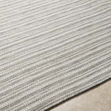 Close-up of the Greg Area Rug in lambswool and smoke, showing the woven texture and subtle striped pattern. Texture