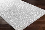 Close-up of the Greensborough Performance Rug on dark wood floor. Gray and white animal print rug. Corner