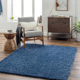 Living room scene with Faina Solid Dark Blue Shag rug, gray chair, wood side table, and mid-century modern dresser. Roomscene-Rectangle